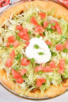 a pizza topped with lettuce, tomatoes and sour cream