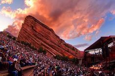 a large group of people sitting on steps in front of a rock formation at sunset