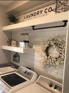 a washer and dryer in a small room with shelves on the wall above them