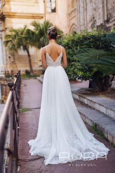 a woman in a wedding dress is walking down the street with her back to the camera