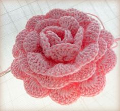 a crocheted pink flower on a white surface