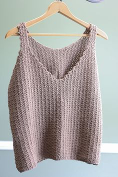 a knitted sweater hanging on a wooden hanger next to a blue and white wall