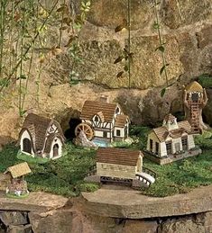 a group of small houses sitting on top of a lush green hillside next to a stone wall