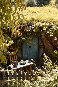 an outdoor table and chair in front of a hobbot with plants growing on it