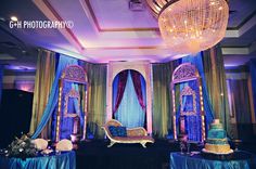 an elaborately decorated stage set up with blue and gold drapes, chandeliers, and cake