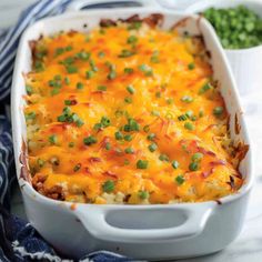 a casserole dish with peas and cheese in it on a blue and white towel