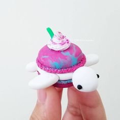 a hand holding a small cupcake with pink frosting and sprinkles