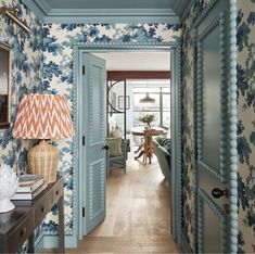 the hallway is decorated with blue and white wallpaper, along with a lamp on an end table