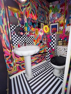 a bathroom with black and white checkered flooring, colorful wallpaper and toilet