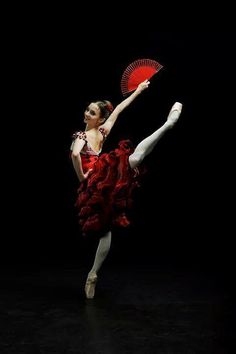 a woman in a red dress is holding a fan and posing for the camera with her leg up