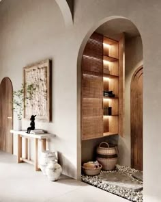 an arched doorway leads to a bathroom with stone flooring and built - in shelving