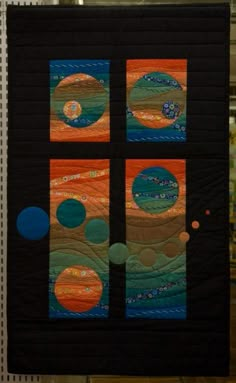 a quilted wall hanging on the side of a building with four different circles in it