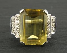 Vintage Large Citrine Diamond Platinum Ring. This is a stunning art deco style platinum cocktail ring with a large emerald cut yellow citrine and sixteen old cut diamonds on the stepped shoulders. Size: 10 (US), U (UK) - finger size.  This ring can be resized for free. The citrine measures 18.5 x 14 mm in length.  Height above finger: 8.37 mm   Citrine carat weight: 12 carats Diamonds weigh 0.25 carat in total. Ring Weight: 11.2 grams This ring is in very good vintage condition with some signs o Yellow Citrine Ring, Amethyst Cocktail Ring, Diamond Sapphire Engagement Ring, Sapphire Diamond Engagement, Diamond Cocktail Ring, Platinum Diamond Rings, Diamond Cocktail Rings, Engagement Ring Sizes, Ring Sale