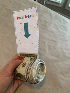 a hand holding a roll of money with a sign that says pull here