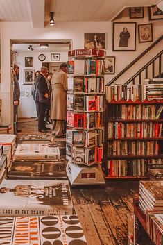 people standing in a room with books on the floor and several shelves full of records