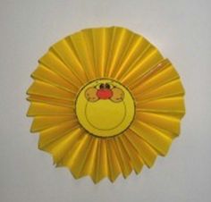 a yellow pinwheel with an image of a bird on it's face, hanging from the ceiling