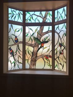 a stained glass window with birds perched on the tree branches in it's center