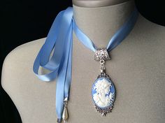 Blue Cameo Choker! This beautiful "Wedgwood Blue" cameo has been set in an antique silver pendant and attached to a blue satin ribbon.... I have added teardrop pearls to the end of each tie... The perfect Mother's Day gift for all those amazing and devoted Mom's! Ribbon is available in light Wedgwood blue, black or pearl greyplease choose from the menu Please select if you would like this item gift wrappedI will also include a card with your personal message.... Thank you for taking time to browse my shop Veronica Rose Designs.... https://www.etsy.com/shop/veronicarosedesigns?ref=seller-platform-mcnav Blue Cameo Jewelry For Wedding, Blue Cameo Necklace For Wedding, Blue Cameo Necklace For Formal Occasions, Victorian Blue Cameo Jewelry, Elegant Oval Cameo Necklace For Wedding, Cameo Pendant Necklace For Wedding, Elegant Cameo Necklace For Vintage Events, Antique Cameo Necklace For Wedding, Blue Medallion Necklaces For Wedding