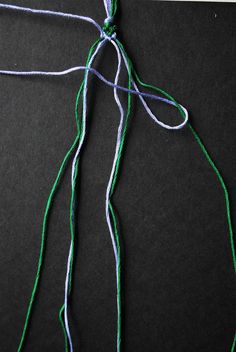 some green and white string on a black surface with scissors next to it that is being used for knitting