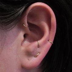 a close up of a person's ear with two small gold rings on it