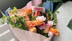 a bouquet of flowers sitting on top of a table next to some books and magazines