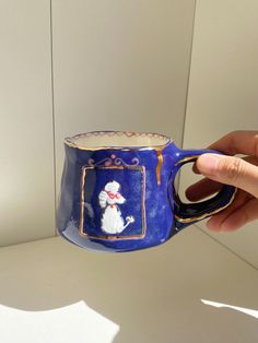 a hand holding a blue mug with a dog on it