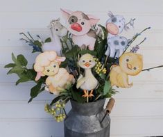 a vase filled with fake farm animals and flowers on top of a wooden table next to a wall