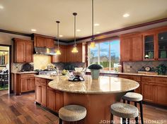 a large kitchen with wooden cabinets and an island in front of the stove top oven