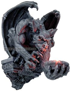 a gargoyle statue holding a lit candle in its mouth