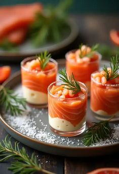 small glasses filled with food sitting on top of a plate next to slices of grapefruit