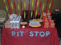 a red table topped with lots of desserts and candy bar signs on top of it