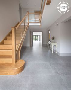 an empty hallway with stairs and table in the middle is seen from across the room