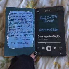 an open book with writing on it and someone's hand holding the book in their left hand