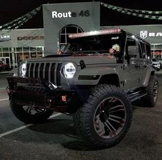 a jeep parked in front of a building at night with lights on it's hood