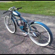 a blue and white motorcycle parked on top of a parking lot next to green grass