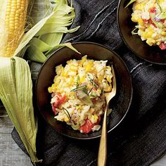 two black bowls filled with food next to corn on the cob and a wooden spoon