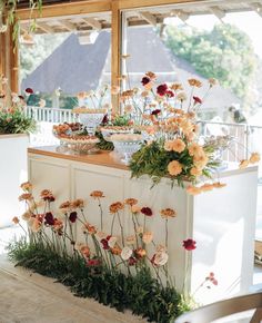 flowers and greenery are arranged on the counter in front of an open air kitchen