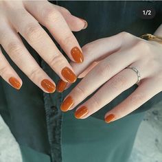 a woman's hands with orange manicures and gold ring on her finger