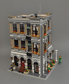 a building made out of legos with people standing outside and looking at the windows