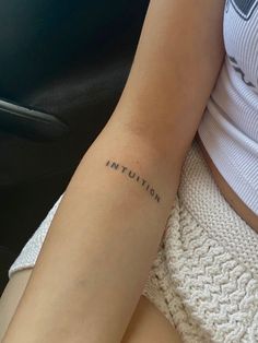 a woman's arm with the word intention tattooed on her left arm, sitting in a car