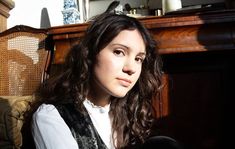 a young woman sitting in front of a fireplace