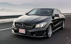 a black mercedes cla driving down the road