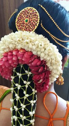 the back of a woman's head with flowers in her hair and beads on it