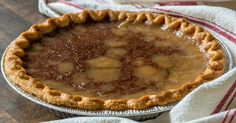 a pie sitting on top of a wooden table next to a red and white towel