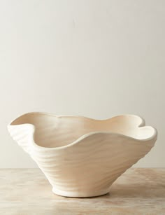 a large white bowl sitting on top of a table next to a wall and floor