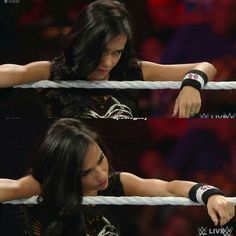 a woman in black shirt standing on top of a wrestling ring with her hands over the ropes