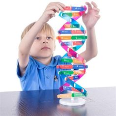 a young boy is holding up a model of a strand of multicolored papers