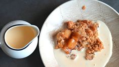 a white plate topped with food next to a cup of coffee on top of a table