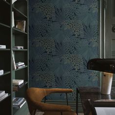 a chair and desk in front of a wallpapered bookcase with books on it