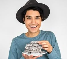 a man in a hat is holding a plate with food on it and smiling at the camera